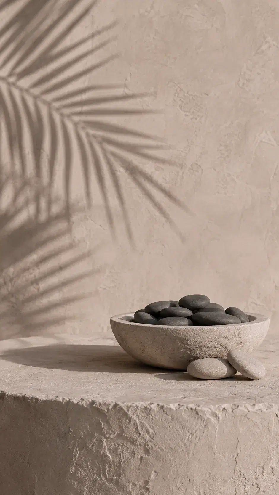 A stone bowl holding dark mineral pebbles in warm light, representing replenished iron stores at WellNest Gold, Cape Town
