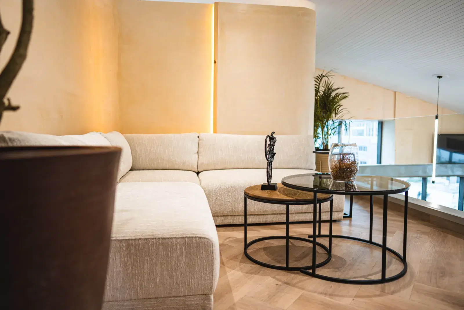 A cream sofa and round coffee tables in the upstairs lounge at WellNest Gold, Cape Town