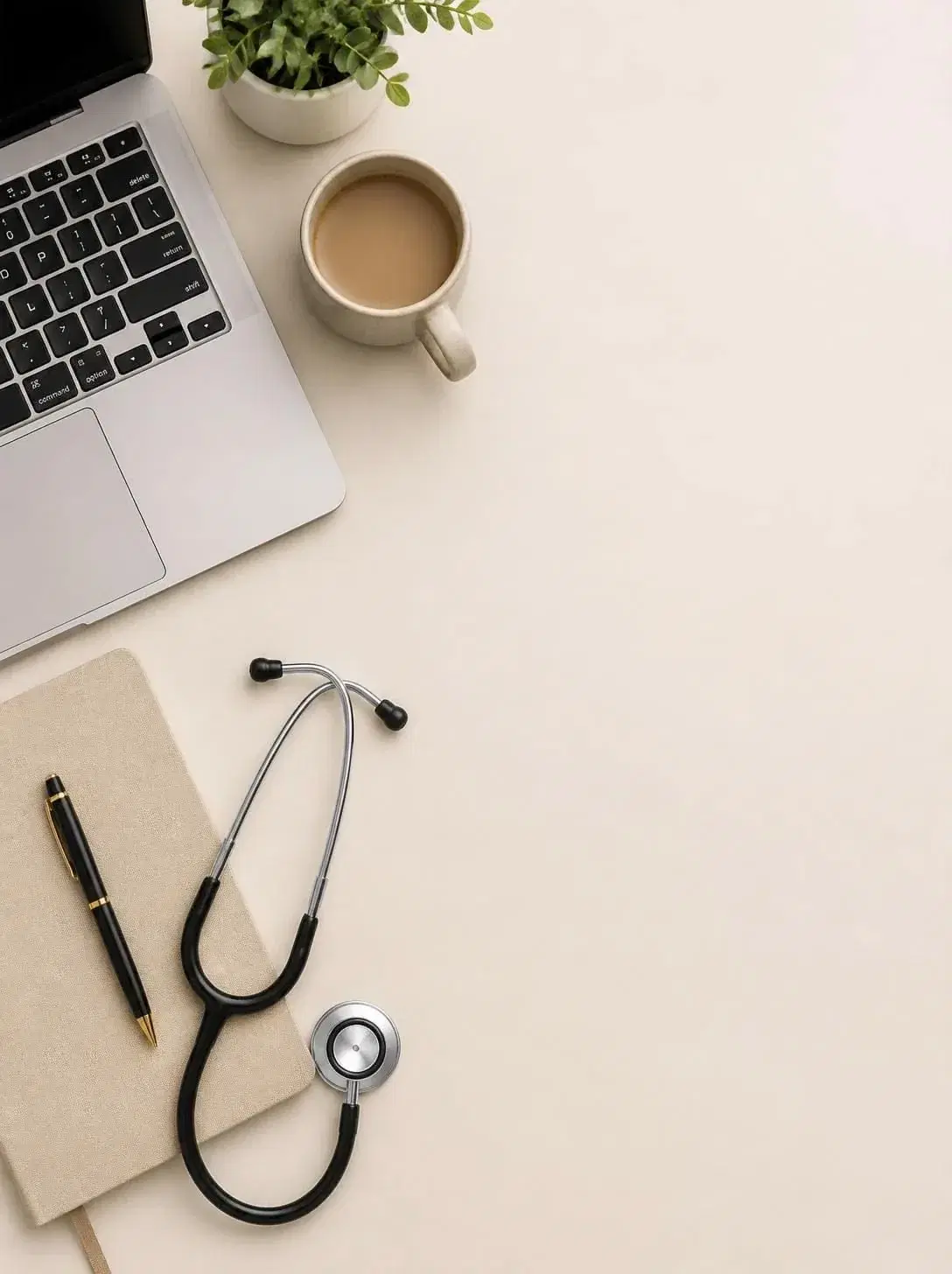 A notebook, pen and stethoscope beside a laptop on a clinician’s desk