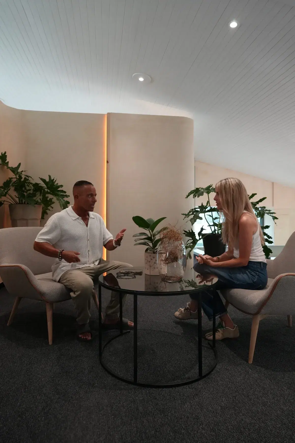A practitioner and a client talking in armchairs beside a low table in the WellNest lounge