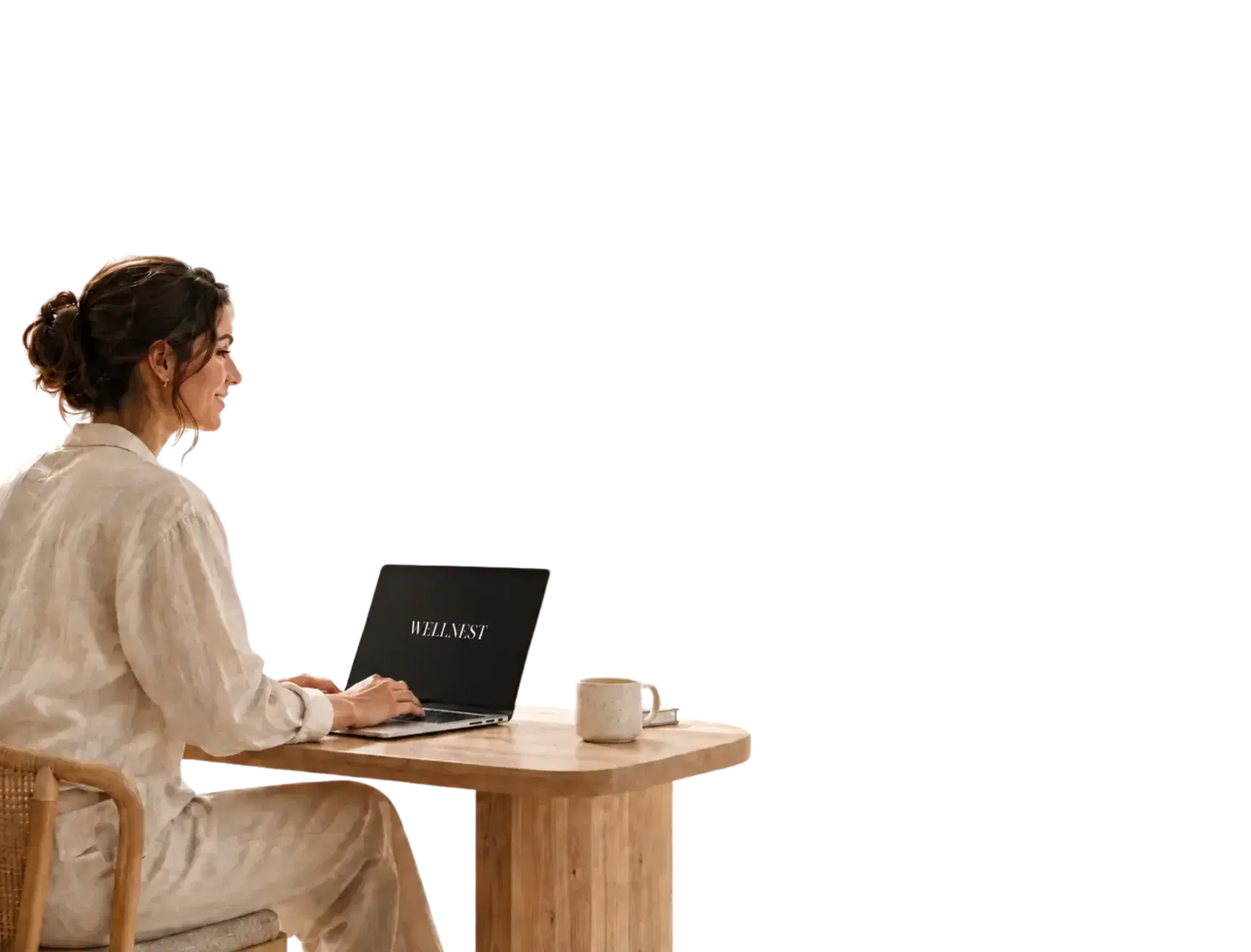 A woman at a wooden table typing on a laptop showing the WellNest wordmark