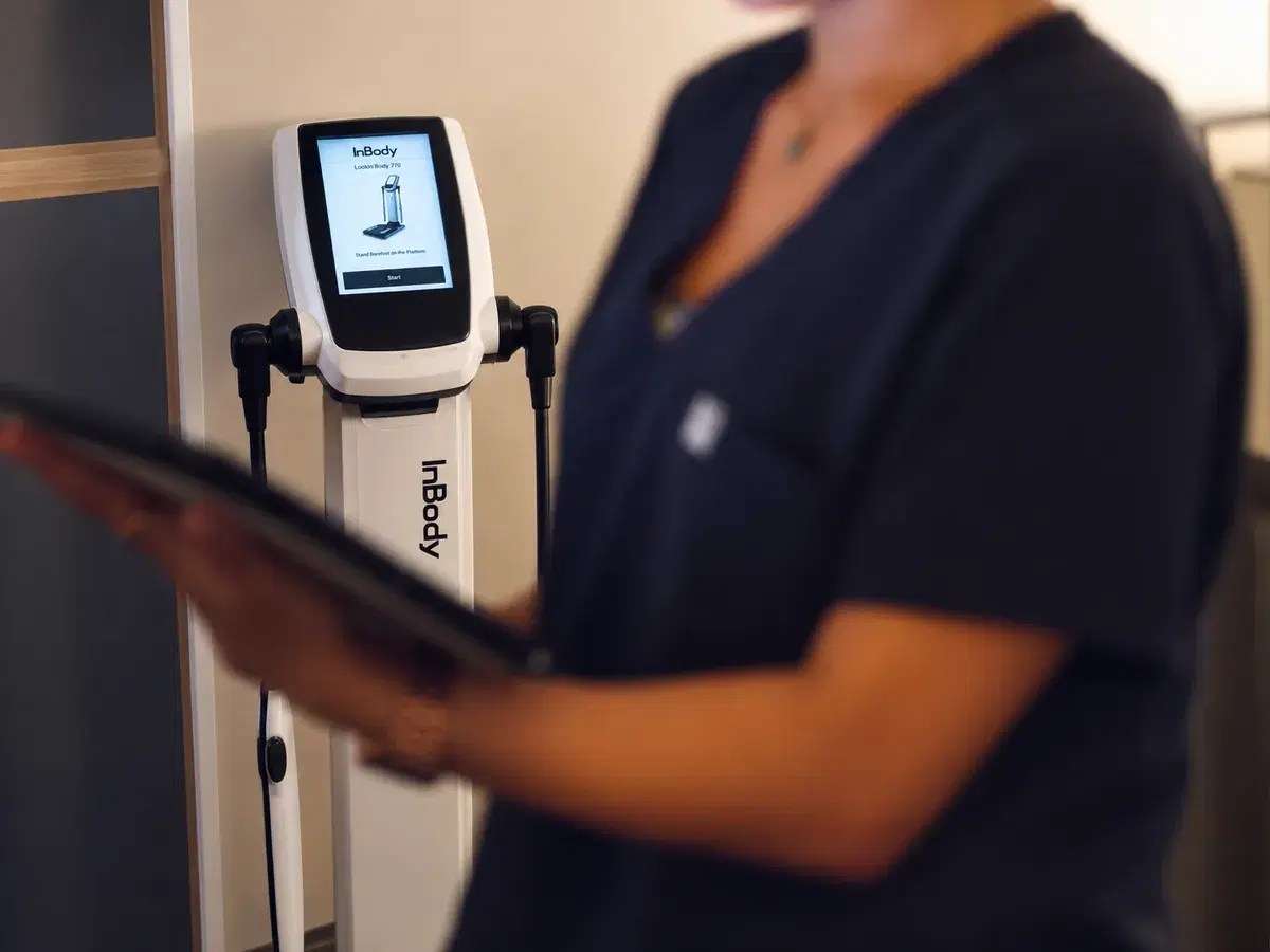 A team member holding a tablet beside the InBody analyser