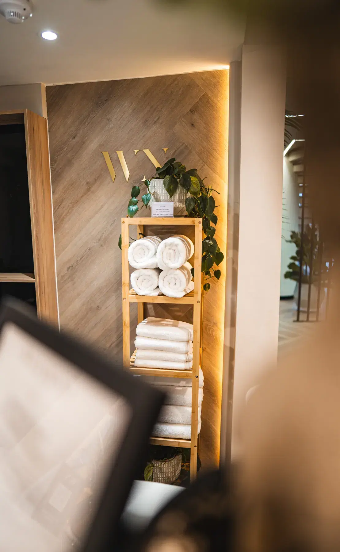 Fresh towels on a shelf under the WellNest monogram in the gym
